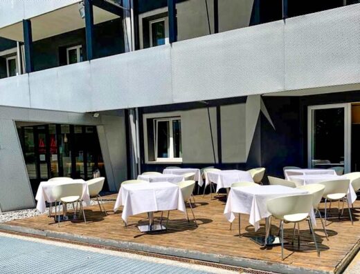 Terrazza esterna dell'Hotel Cavallo con tavoli apparecchiati e sedie moderne, ideale per un pranzo o una cena all'aperto durante il tuo viaggio.