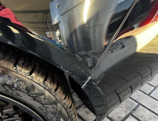 Dettaglio di una motocicletta nera con graffi sulla carrozzeria vicino alla ruota. Servizi di riparazione carrozzeria moto offerti da CBC srl.