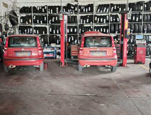 Interno di Centro Autoservizi: due auto rosse Fiat Panda su ponte sollevatore per manutenzione e cambio gomme. Ampia scelta di pneumatici.
