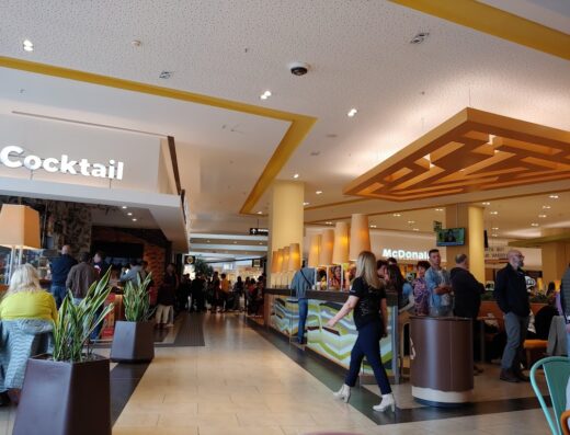 Interno del Centro Commerciale Le Terrazze con persone in fila al bar "Cocktail" e al McDonald's, illuminazione interna e segnaletica.