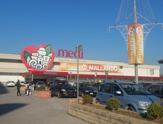 Foto del Centro Commerciale Medì, con parcheggio auto e insegne dei negozi Expert Mallardo. Luogo ideale per shopping e servizi.