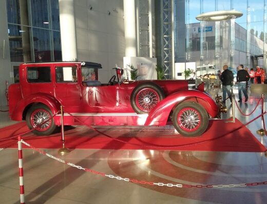 Auto d'epoca rossa esposta al Centro Fiera del Garda, dettaglio degli interni e degli accessori vintage. Presenza di visitatori sullo sfondo.