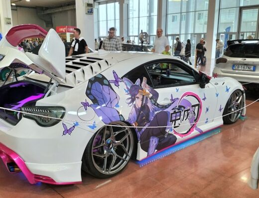Auto sportiva bianca personalizzata con grafica anime esposta al Centro Fiera SpA, con accessori tuning e illuminazione a LED.