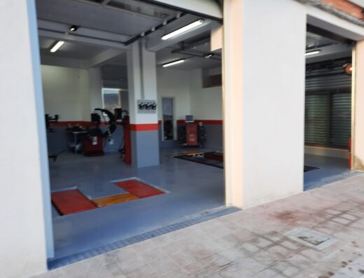 Interno di un'officina First Stop Ok Gomme, specializzata in servizi per pneumatici moto e auto, con attrezzature per la riparazione e sostituzione gomme.