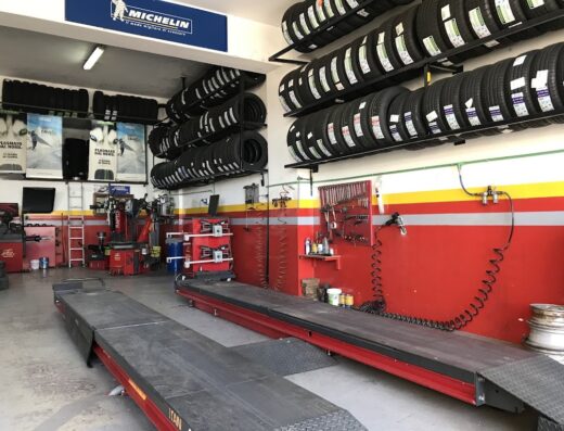 Interno di Centro Gomme e Revisioni di Macheda Giuseppe, con scaffali di pneumatici Michelin, attrezzature per la riparazione e banchi di lavoro.