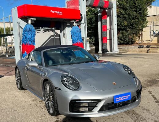 Lavaggio auto a Centro Lavaggio Tuscia: Porsche 911 argento cabriolet in un impianto di autolavaggio automatico con spazzole colorate.