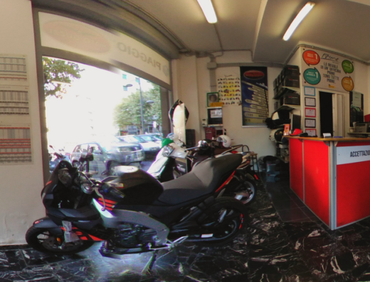 Interno di Centro Moto Trieste snc con moto Aprilia in primo piano e zona accettazione. Vendita, riparazione e accessori moto.