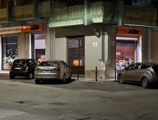Esterno del negozio CentroMoto&Bike che offre vendita e assistenza per moto e bici nuove e usate, con vetrine illuminate che mostrano modelli KTM.