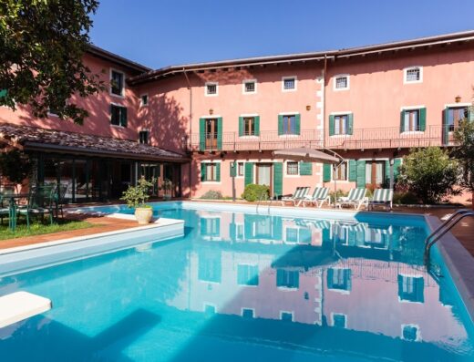 Ciasa De Gahja: Vista della piscina esterna con riflessi dell'edificio, sdraio e ombrellone per il relax dei visitatori.