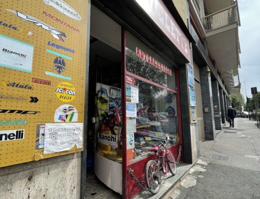 Ingresso del negozio Cicli Quagliotti di Martelli Luca, con vetrina di biciclette Bianchi e accessori, e una bici da bambino rosa esposta all'esterno.
