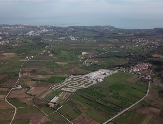 Vista aerea del Circuito Internazionale d'Abruzzo, una pista di karting circondata da campi verdi, colline e il mare Adriatico sullo sfondo. Ideale per gli appassionati di moto e kart che cercano un'esperienza di guida emozionante.