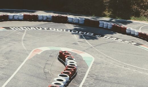 Vista della pista del Club del Miniautodromo di Massa, con pneumatici di protezione e segnaletica tricolore, ideale per appassionati di moto e minimoto.