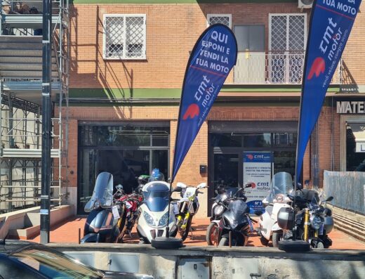 Esposizione di moto usate in vendita da CMTmotor Roma Via Prenestina, con bandiere promozionali che invitano a esporre e vendere la propria moto, vendita moto e scooter