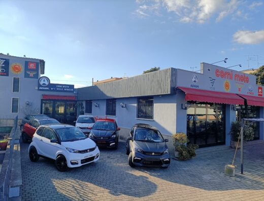Co.mi Moto dealership exterior with several parked microcars, showcasing Aixam and other brands for sale.