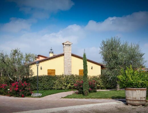 Country house in Valle del Metauro, Italia, con giardino curato, ulivi, fiori e cielo azzurro. Ideale per un soggiorno rilassante e per esplorare la regione in moto.