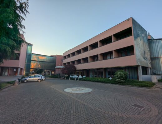 CSHRE City Style Hotel Reggio Emilia exterior view, showcasing the building's facade, entrance area with a car parked, and architectural details under a clear sky.