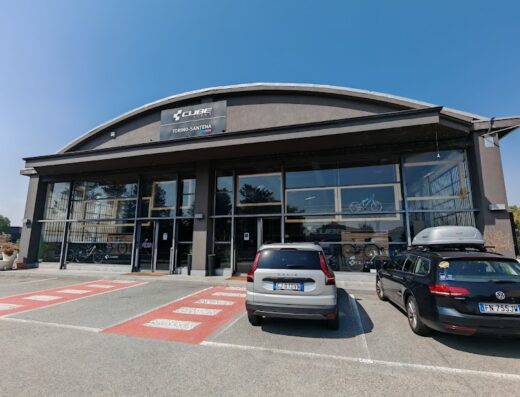 Cube Store Torino-Santena: negozio di biciclette Cube con esposizione di modelli e accessori. Parcheggio con auto di fronte all'ingresso.