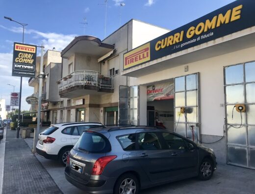 Curri Gomme Driver Center Pirelli, centro collaudi pneumatici e assistenza auto con insegna Pirelli e auto parcheggiate