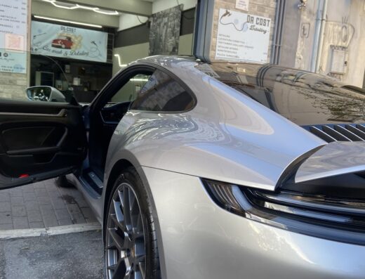 Auto di lusso grigia parcheggiata di fronte a Da Cost Car Wash & Detailing, con porta aperta e dettagli della carrozzeria in evidenza.