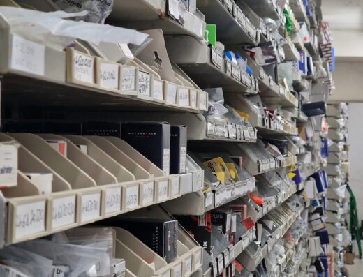 Scaffalatura piena di ricambi e accessori per moto da DACARMOTO, con etichette identificative, ideale per manutenzione e riparazione moto.