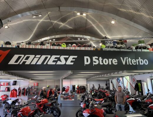 Interno del Dainese D-Store Viterbo con moto Ducati esposte, abbigliamento tecnico per motociclisti e caschi in vendita.