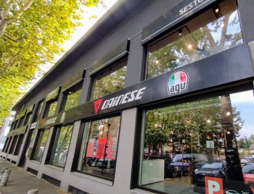 Dainese Milano Nord Outlet store front, featuring Dainese and AGV logos, displaying motorcycle apparel and accessories in Sesto San Giovanni, Italy.