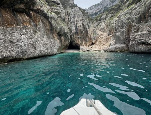 Noleggio gommoni a Cala Gonone: Vista dal gommone sull'acqua cristallina verso una spiaggia incastonata tra le rocce.