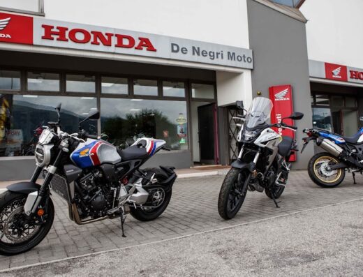 Showroom of De Negri Moto featuring a Honda CB1000R motorcycle with a custom paint job, a Honda CB500X adventure bike, and a Honda Africa Twin adventure touring motorcycle.