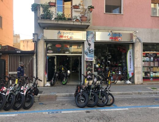 Di Penta Moto store front with electric bicycles parked outside, motorcycle helmets and accessories visible in the window.