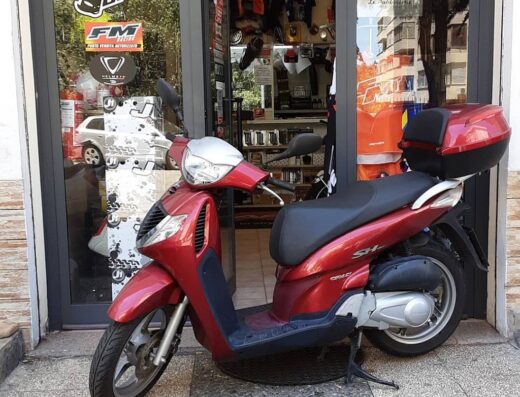 Una moto scooter rossa parcheggiata davanti al negozio DM Moto di Marra Domenico, specializzato nella vendita, riparazione e ricambi di auto e moto.