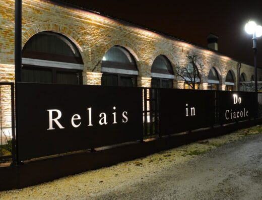 Esterno notturno del Relais Do Ciacole, con insegna illuminata e architettura in mattoni a vista, ideale per viaggi e relax.