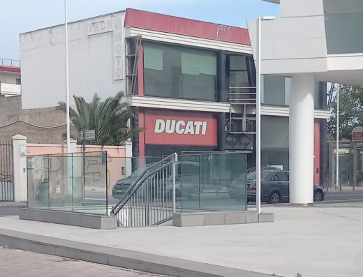 Ducati Cagliari Joe Cow Motos: Concessionaria Ducati con insegna rossa ben visibile, vetrine ampie e accesso tramite scala esterna.