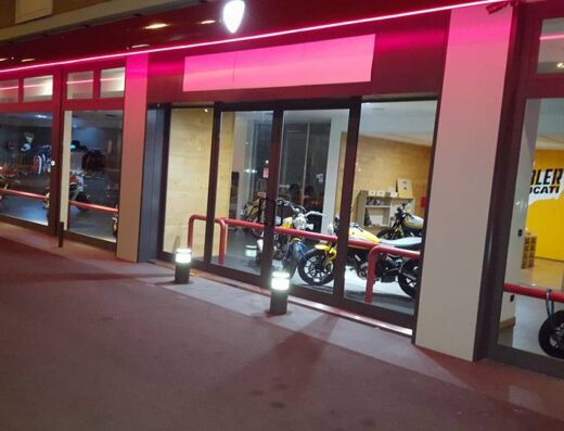 Vetrine illuminate di Ducati Modena, con moto esposte e insegna luminosa, concessionaria di moto e accessori per motociclisti.