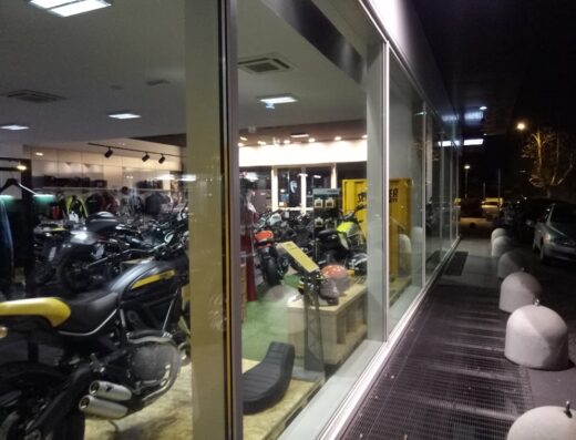 Vetrine illuminate del concessionario Ducati Pescara che mostrano una varietà di moto Ducati, abbigliamento e accessori per motociclisti.