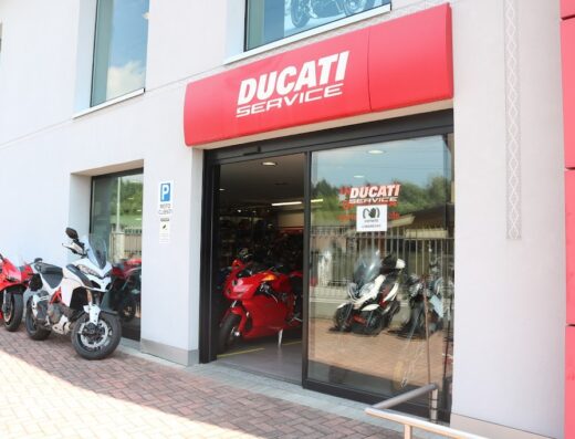 Ducati Varese: Concessionario e officina Ducati. Parcheggio moto clienti e ingresso con vetrina che espone modelli di moto Ducati.