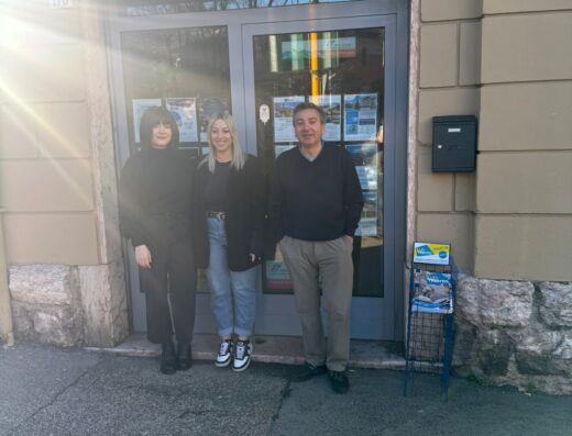 East West Tours Italia Srl office front with three people standing outside. The office has a sign that reads "Agenzia Viaggi EWT".