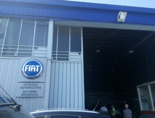 Officina autorizzata Fiat con insegna ben visibile, ricambi originali e personale al lavoro all'interno. Servizi di assistenza e riparazione auto.