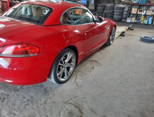 Auto sportiva rossa in un'officina di Efa Gomme per la vendita e l'assistenza pneumatici. Si vedono degli pneumatici accatastati.