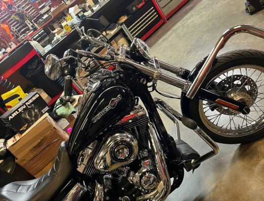 Una motocicletta Harley-Davidson nera e cromata in un'officina con scaffali di attrezzi, ideale per il servizio Effe Motors S.R.L.