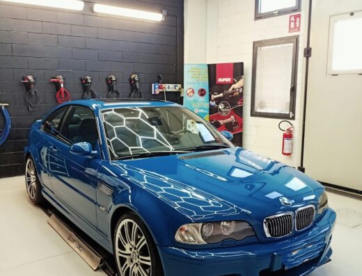Auto blu Effeuno in un'officina di car detailing con illuminazione a nido d'ape, che mostra i servizi di cura e pulizia dell'auto.