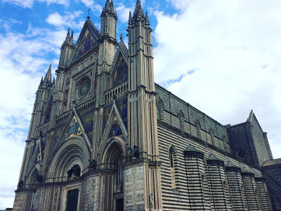 Cattedrale di Orvieto, Umbria, Italia: vista esterna della facciata gotica con dettagli artistici e architettonici unici, cielo azzurro sullo sfondo. Elle Viaggi.