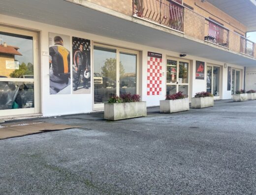 EM MOTO S.r.l., negozio di accessori e abbigliamento moto a Reggio Emilia. Vetrina con poster di giacche e caschi da motociclista.