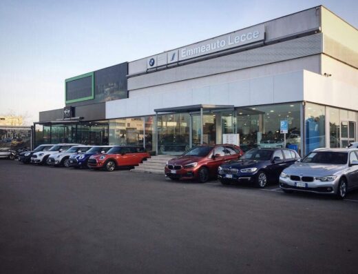 Emmeauto Lecce Srl, concessionaria BMW e MINI, mostra una selezione di auto BMW e MINI parcheggiate di fronte all'edificio.