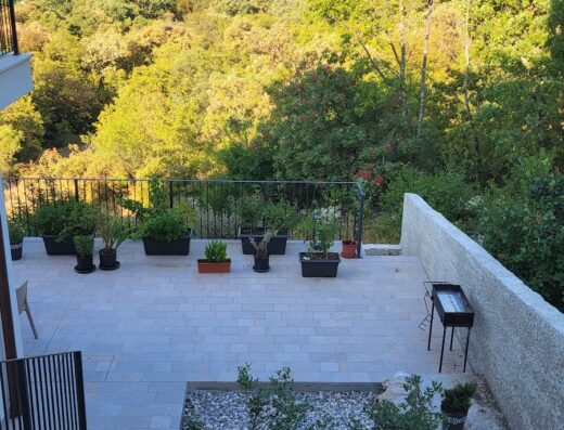 Vista panoramica dall'Encanto Agriturismo & Private SPA con terrazza fiorita, barbecue e sfondo di mare e colline verdi.