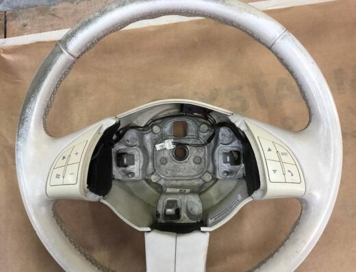 Volante di un'auto Fiat bianco sporco, con comandi integrati. Accessorio auto usato, ideale per ricambi o restauro. Eni Pratesi marketplace.