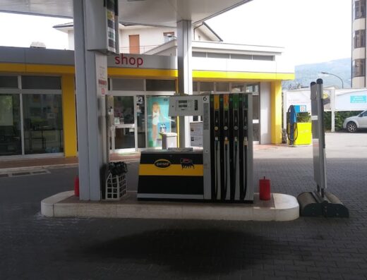 Stazione di servizio Eni con distributore di carburante, insegna del negozio e auto parcheggiata. Servizi per motociclisti e automobilisti.
