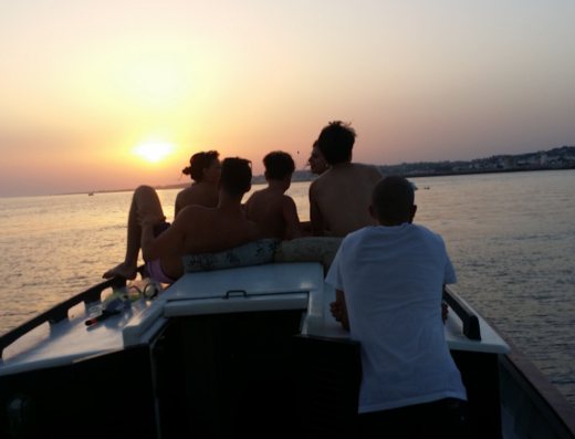 Gruppo di persone rilassate su una barca al tramonto durante un'escursione Maretta. Godetevi il viaggio in mare con amici e famiglia.