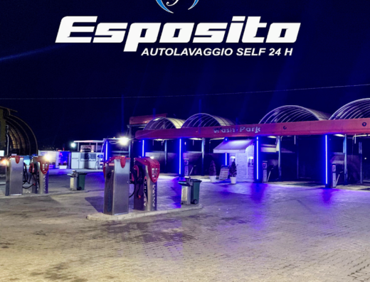 Esposito Autolavaggio Self 24h: vista notturna dell'autolavaggio self-service con postazioni per la pulizia di moto e auto, illuminazione blu e insegna ben visibile.