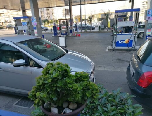 Stazione di servizio Q8 con auto parcheggiate, pompe di benzina e distributori visibili, ideale per rifornimento durante viaggi in moto.