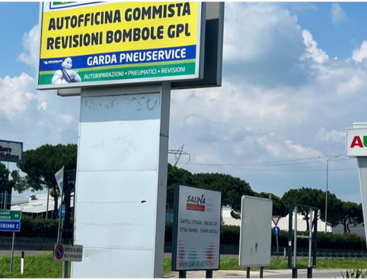 Cartello stradale di Euromaster Garda Pneuservice, officina per autoriparazioni, pneumatici e revisioni auto e moto a Garda, con indicazioni stradali e cartelli pubblicitari.